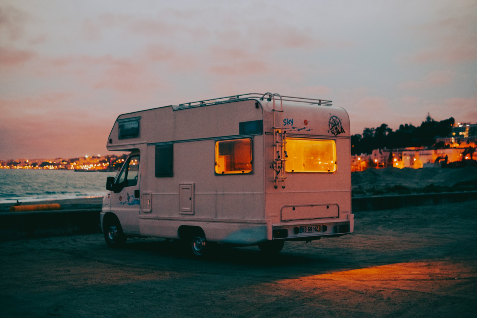 a white bus parked next to a body of water, RV